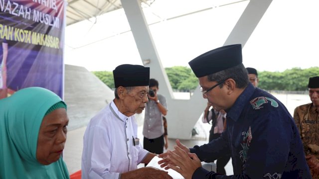 Wali Kota Makassar, Moh. Ramdhan Pomanto menyerahkan bantuan kepada warga yang mengabdi di bidang keagamaan, berlangsung di Tribun Lapangan Karebosi, Jumat (21/12/2018).
