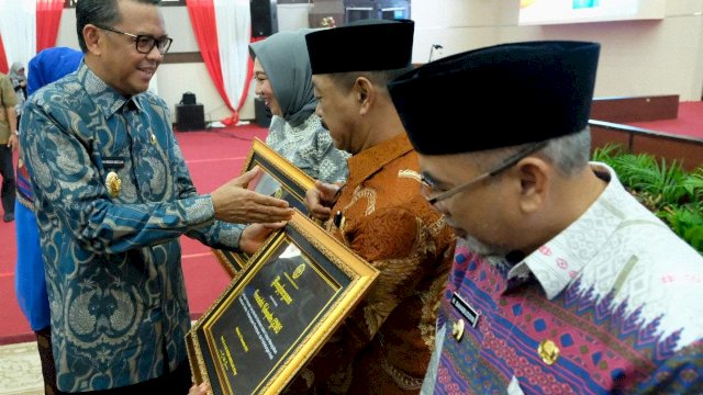 Gubernur Sulsel, Nurdin Abdullah, menyerahkan penghargaan Pada Peringatan Hari Ibu ke-90 kepada Wakil Bupati Gowa, Abdul Rauf Malaganni yang berlangsung di Ruang Pola Kantor Gubernur Sulsel, Kamis (27/12/2018).
