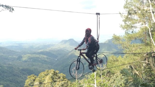 Salah seorang wisatawan lokal menikmati gasilitas sepeda melayan yang ada di Kawasan Wisata Alam Lembah Cinta, Desa Mattabulu, Kabupaten Soppeng, Minggu (24/02/2019).