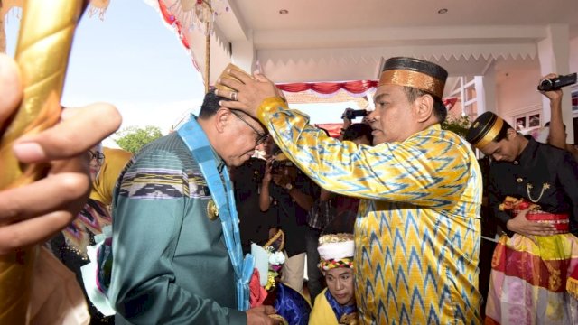 Bupati Bone, Andi Fashar Padjalangi memakaikan songkok recca to bone, kepada Gubernur Sulsel Nurdin Abdullah, Jumat (05/04/2019).
