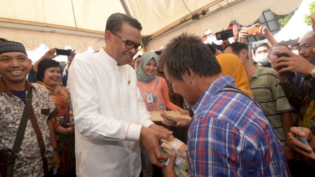 Gubernur Sulsel, Nurdin Abdullah melayani salah seorang warga yang menukarkan uang dihari pertama pembukaan layanan BI, di Lapangan Upacara Kantor Gubernur, Jumat (10/05/2019).
