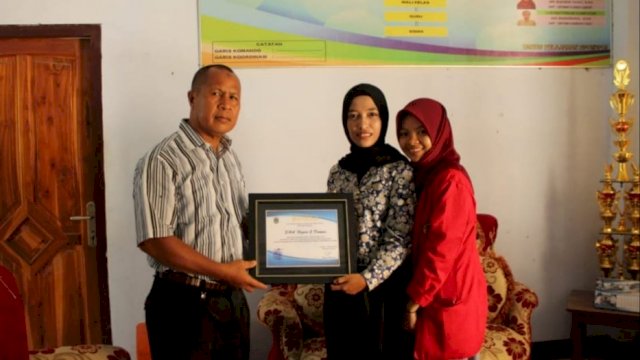 Guru SMAN 2 Dompu, Amin, menerima plakat dari Ikatan Mahasiswa (IWA) Mbojo Unhas usai sosialisasi di Dompu, Sabtu (11/01/2020).