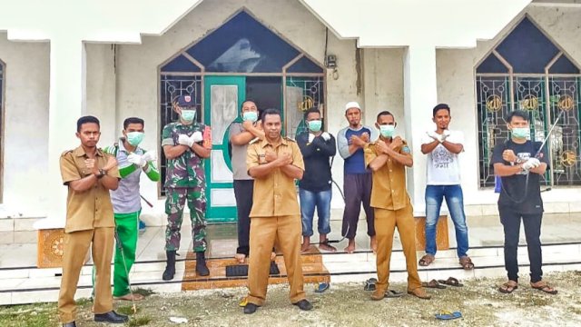 Kepala Desa Balobone, Sabandia, dan petugas berforo bersama dengan menyilangkan tangan sebagai simbol perlawanan terhadap covid-19, Senin (30/03/2020).