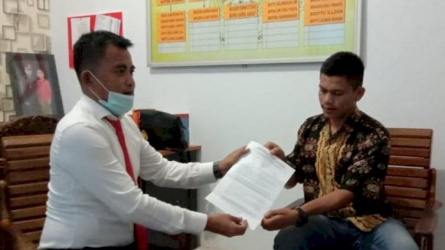 Ketua Aliansi Pemuda dan Mahasiswa Kabupaten Muna Yogi mengkuo, menyerahkan berkas laporan kepada Kasat Reskrim Polres Muna Iptu Hamka, Selasa (21/07/2020).