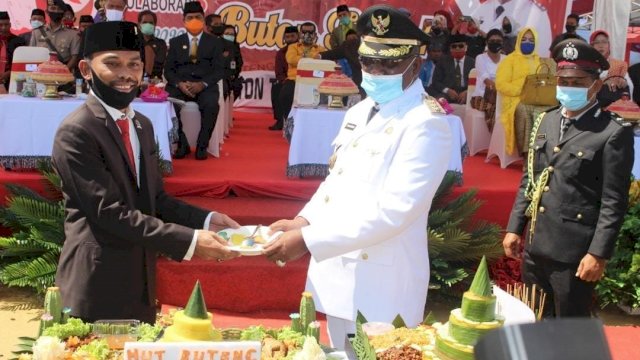 Bupati Buteng Samahuddin (La Ramo) menyerahkan potongan nasi tumpeng HUT Ke-6 Buton Tengah, kepada Ketua DPRD Bobi Ertanto, di Lapangan Lapangan Lamedadi, Kamis (23/07/2020).