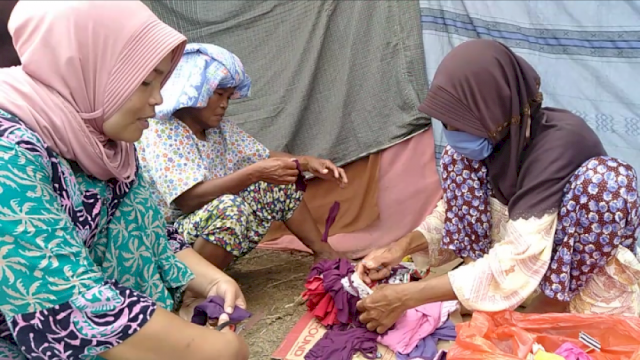 Ibu ibu korban banjir bandang Masamba membuat keset dari pakaian bekas di camp pengungsian