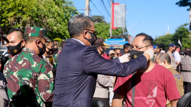 Gubernur Sulsel Prof. Nurdin Abdullah, memakaikan masker secara simbolis kepada salah satu pengguna jalan di Depan Karebosi, Jl. Ahmad Yani Makassar, Kamis (10/09/2020).