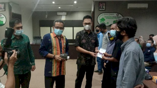 Stafsus Presiden RI Aminuddin Ma'ruf didampingi Rektor UHO Prof. Zamrun Firihu saat menyerahkan rekening KIP kepada perwakilan mahasiswa peserta KIP. Foto: Akbar Tanjung