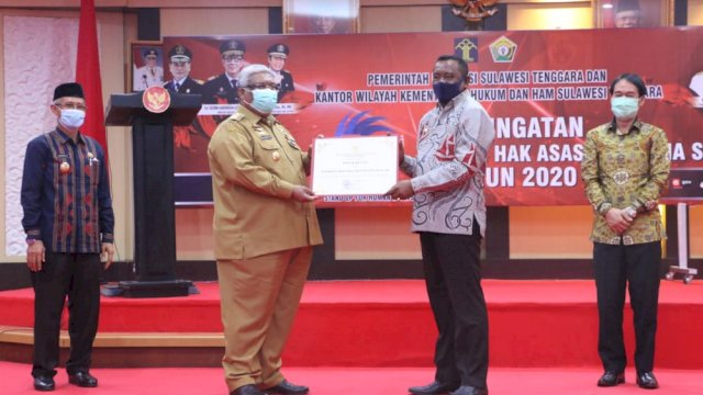 Gubernur Sultra Ali Mazi saat menyerahkan piagam penghargaan kepada Bupati Buton Tengah Samahuddin