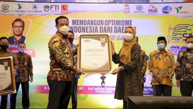 Plt Gubernur Sulawesi Selatan, Andi Sudirman Sulaiman menyerahkan penghargaan dari SMSI kepada Bupati Luwu Utara Indah Putri Indriani sebagai kepala daerah peduli media dan pers di Hotel Claro Makassar. Jumat (26/03/202)