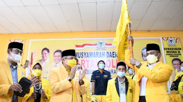 Usman Marham mengibarkan bendera Partai Golkar setelah terpilih memimpin DPD II Golkar Pinrang, Minggu (25/04/2021).