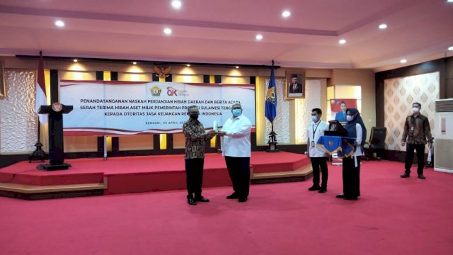 Gubernur Ali Mazi saat memberikan cendra mata kegiatan penyerahan hibah aset Pemprov Sultra ke OJK. Foto: Akbar Tanjung