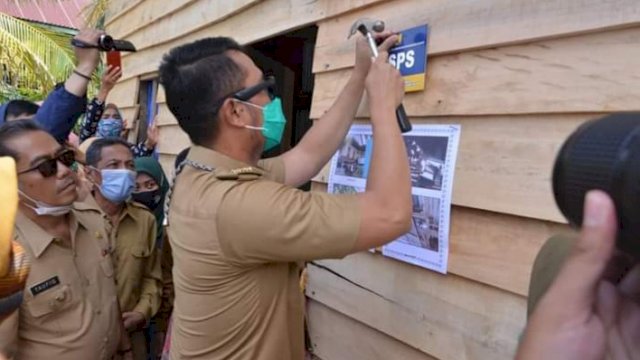 Bupati Sinjai Andi Seto Asapa, menempel plang di salah satu rumah yang mendapatkan bantuan rumah beberapa tahun lalu.
