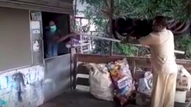 Petugas Kantor Kelurahan Galung, Kecamatan Liliriaja, Kabupaten Soppeng, memberikan bantuan sembako menggunakan tangkai kayu kepada warga yang sedang melakukan isolasi mandiri akibat terkonfirmasi covid-19, Senin (09/08/2021).