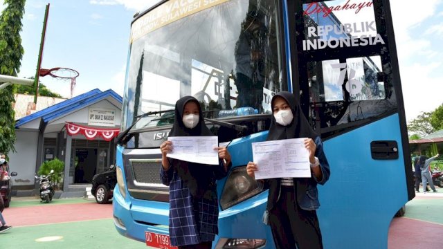Dua orang pelajar menunjukkan bukti Vaksin.