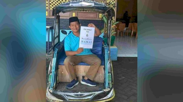 Kepala Desa Galesong Kota memegang kertas bertulis pilih nomor 6 di atas bentor.