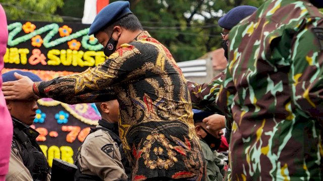 Plt Gubernur Sulsel Andi Sudirman Sulaiman, memakaikan baret ke salah satu Anggota Brimob Polda Sulsel, saat menghadiri 76 Tahun Brimob.