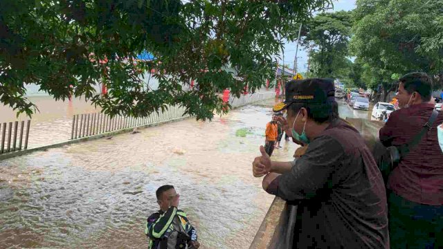 Plt Gubernur Sulsel Andi Sudirman Sulaiman, menyapa Polisi Laku Lintas Kabupaten Takalar yang sedang bertugas, saat meninjau banjir dari atas Bak Truk, Selasa (07/12/2021).