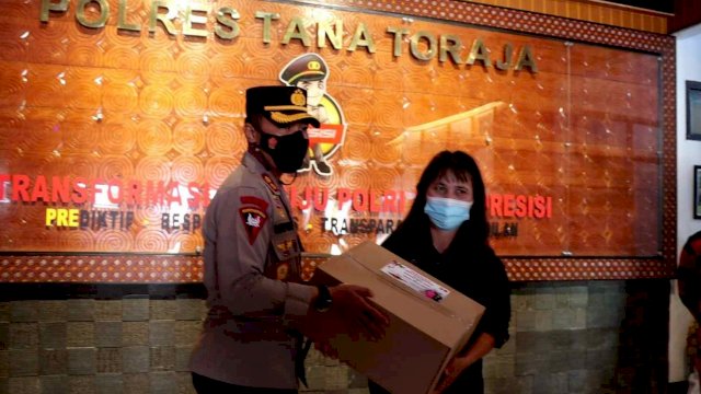 Kapolres Tana Toraja AKBP Sarly Sollu, memberikan bingkisan kepada salah satu awak media, di Ruang Loby Mapolres Tana Toraja, Senin (20/12/2021).