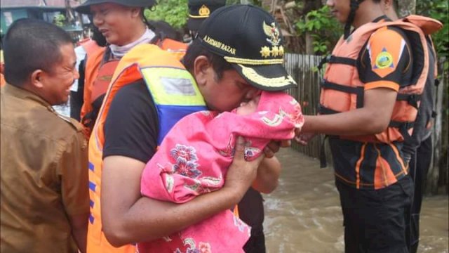 Bupati Soppeng Andi Kaswadi Razak, menggendong bayi yang terjebak banjir luapan Sungai Walennae, Rabu (08/12/2021).