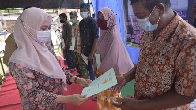 Bupati Luwu Utara menyerahkan sertifikat tanah kepada salah satu masyarakat Desa Sepakat. Minggu (05/12/2021)