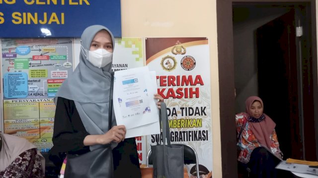 Salah seorang warga Sinjai memperlihatkan kartu vaksin Covid-19 dosis lengkap saat melakukan pengurusan administrasi di Polres Sinjai, Senin (03/01/2022).