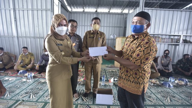 Bupati Luwu Utara Indah Putri, Indriani menyerahkan kunci hunian tetap (Huntap) kepada salah satu penyintas banjir bandang, Selasa (15/02/2022). (Foto. Bayu Firmansyah/Republiknews.co.id)