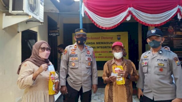 Kapolsek Tamalatea AKP Muh.Natsir terlihat membagikan minyak goreng ke warga yang ikut vaksinasi, Sabtu (19/03/2022). (Istimewa)