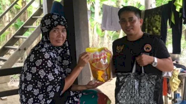 Ketua Garda Pemuda NasDem Sidrap Saenal Rosi, menyerahkan minyak goreng kepada salah satu warga Desa Tonronge, Kecamatan Baranti, Sidrap, Jumat (25/03/2022). (Istimewa)