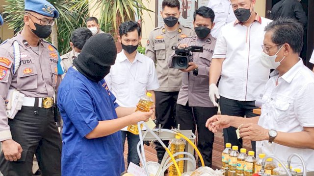 Tersangka AR memperagakan cara mengemas ulang minyak goreng saat press confrence, Rabu (30/03/2022). (Istimewa)