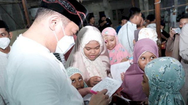 Bupati Gowa Adnan Purichta Ichsan saat menandatangani buku Amalia Ramadan anak-anak usai melaksanakan salat tarawih di Masjid Nurul Izzah, Dusun Cambayya, Desa Jennetallasa, Kecamatan Pallangga, Rabu (13/4/2022) malam kemarin. (Istimewa)