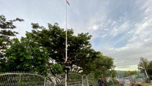 Anggota Polisi memanjat Tiang Bendera untuk menurunkan Bendera Bintang Kejora, di Distrik, Jayapura Utara, Jayapura, Papua, Minggu (01/05/2022). (Istimewa)