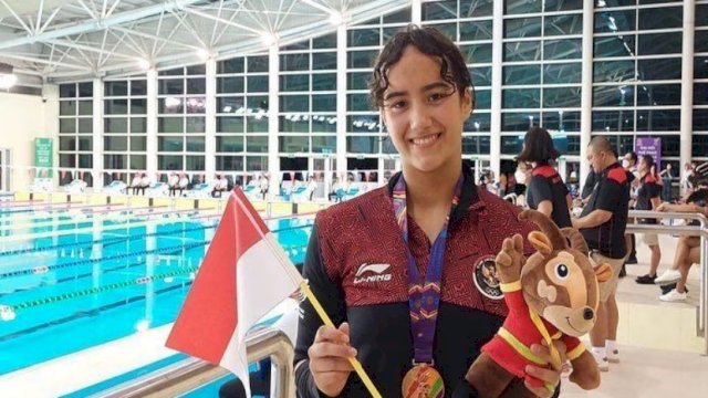 Perenang Indonesia di Sea Games 2022 Vietnam, Masniari Wolf mengenakan Medali Emas yang ia peroleh sembari memegang Bendera RI. (Foto: Antara)