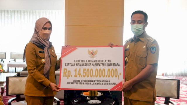 Gubernur Sulsel Andi Sudirman Sulaiman, menyerahkan bantuan keuangan secara simbolis kepada Bupati Luwu Utara Indah Putri Indriani, Senin (06/06/2022). (Istimewa)