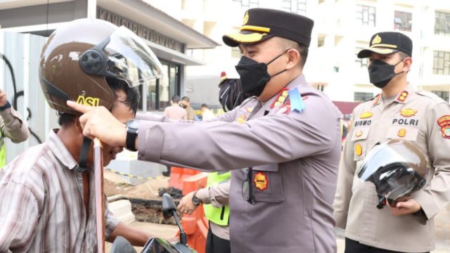 Kapolres Metro Jakarta Barat Kombes Pol Pasma Royce memakaikan helm ke Pengguna Jalan saat Operasi Patuh Jaya 2022. (Istimewa)