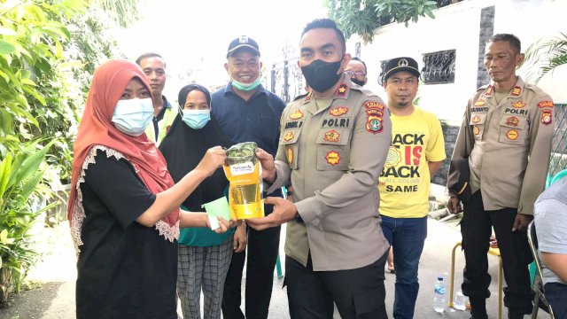 Kapolsek Cengkareng Kompol Ardhie Demastyo, menyeragkan minyak Goreng ke warga saat melakukan vaksinasi, Rabu (29/06/2022). (Istimewa)