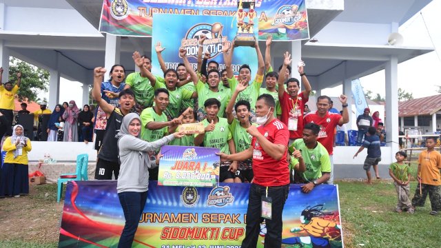 Bupati Luwu Utara Indah Putri Indriani menyerahkan piala kepada keseblasan Prima Putra Burau sebagai juara pada turnamen sepakbola Sidomukti Cup I. Minggu (12/06/2022)