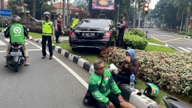 Kendaraan Mercy tampak naik ke Median jalan kawasan SCBD Jaksel, nampak pengemudi ojol duduk mengalami luka-luka. (Foto: Twitter TMC Polda Metro Jaya)