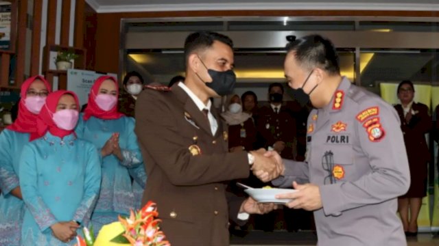 Kajari Jakbar Dwi Agus Afrianto, memberikan potongan nasi tumpeng kepada Kapolres Metro Jakbar Kombes Pol Pasma Royce, Jumat (22/07/2022). (Istimewa)