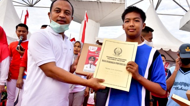 Gubernur Sulsel Andi Sudirman Sulaiman, saat menyerahkan beasiswa kepada salah datu Siswa, Jumat (12/08/2022). (Istimewa)