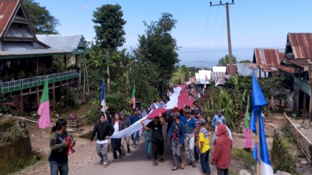 Ratusan warga Desa Ujungbulu, Kabupaten Jeneponto, mengarak bendera merah putih sepanjang 77 meter keliling kampung untuk selanjutnya dikibarkan ke Puncak Gunung Bontolonjong, Senin (15/08/2022). (Istimewa)