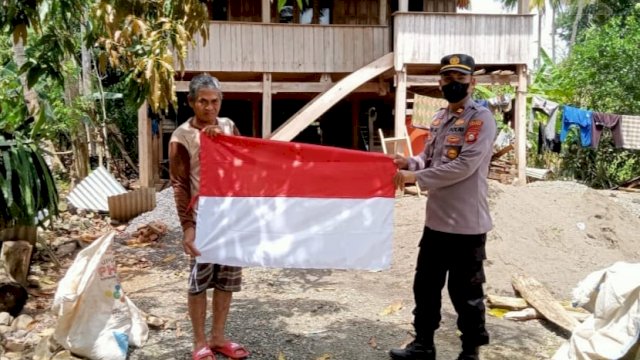 Anggota Polres Soppeng memberikan bendera merah putih kepada salah satu warga, Selasa (16/08/2022). (Ist)