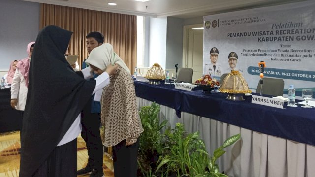 Kadisparbud Kabupaten Gowa Andi Tenriwati Tahri saat membuka Pelatihan Pemanduan Wisata Buatan ditandai pengalungan tanda nama ke salah satu peserta, di Hotel Aryaduta Makassar, Rabu (19/10/2022). (Foto: Chaerani/Republiknews.co.id)
