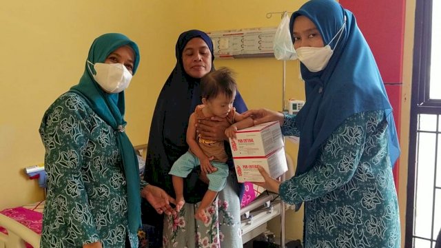 Ketua TP-PKK Luwu Utara, Ny. Rahma Nursaid Suaib, memberikan bantuan makanan tambahan kepada seorang balita