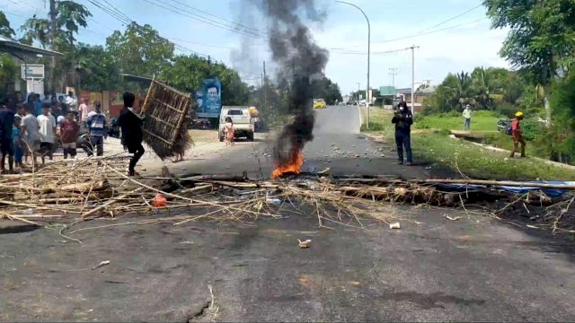 Massa di berbagai wilayah di Kabupaten Takalar, menggelar aksi unjuk rasa dengan menutup akses jalan poros Galesong menuju Makassar, Rabu (16/11/2022). Aksi ini sebagai bentuk protes terhadap hasil ujian tulis Calon Kepala yang dianggap manipulasi. (Istimewa)