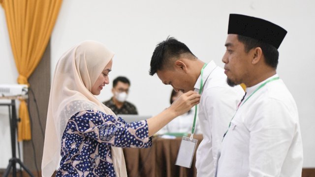 Bupati Luwu Utara menyematkan tanda peserta kepada salah satu kepala desa di Luwu Utara yang mengikuti orientasi aparatur desa.