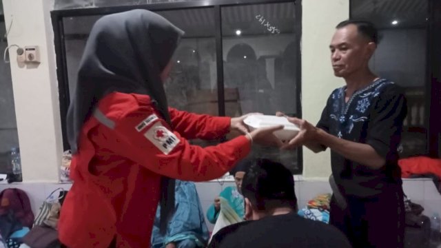 Petugas PMI Kota Makassar saat memberikan bantuan makanan kepada salah satu warga terdampak bencana banjir, Senin (13/02/2023). (Istimewa)