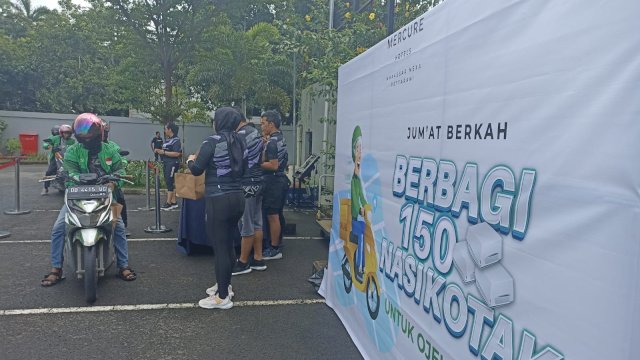 General Manager Mercure Makassar Wiwied Nurseka (kanan) saat membagikan makanan kepada driver ojek online pada program Jumat Berkah Berbagi 150 Nasi Kotak untuk Ojek Online, di Parkiran Mercure Makassar, Jumat (03/03). (Chaerani/Republiknews.co.id)
