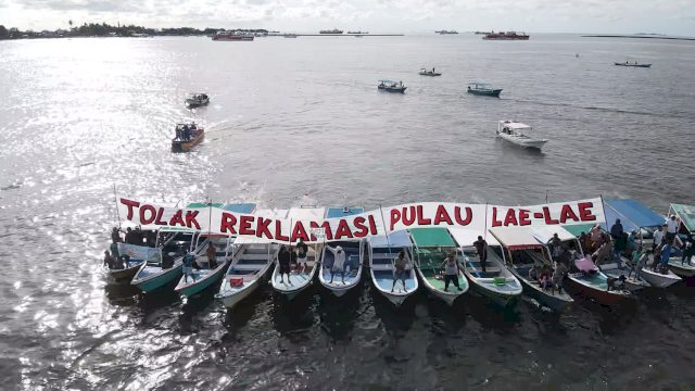 Warga Pulau Lae-Lae saat melakukan aksi di atas perahu sebagai bentuk pernyataan sikap menolak rencana reklamasi Pulau Lae-Lae yang akan direncanakan Pemerintah Provinsi Sulawesi Selatan, di Pantai Losari, Sabtu (04/03/2023). (Dok. Kawal Pesisir)