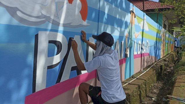 Seniman muda yang tergabung dalam Ritus Art Makassar saat mendesain Lorong Wisata Milenial Pintu Nol Universitas Hasanuddin yang berada di Kelurahan Tamalanrea Indah, Kecamatan Tamalanrea agar lebih cantik dan indah, Minggu (19/03). (Chaerani/Republiknews.co.id) 
